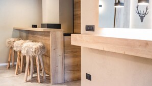 Een receptiegedeelte met een houten balie, twee stoelen met beklede kussens en hangende lampen.