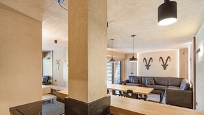 Een moderne keuken met een centraal eiland, een eethoek met een houten tafel en stoelen, en een zithoek met een bank en decoratie aan de muur.