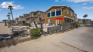 Une propriété située en bord de mer, avec une maison en bois, un espace salon extérieur et des palmiers.