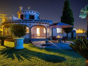 A house with a patio, outdoor seating, and a well-maintained lawn.
