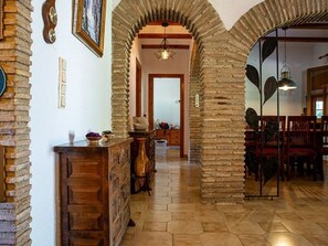 A hallway with brick walls, wooden cabinets, and a dining area with red chairs.