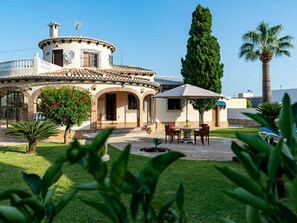 Una casa con patio, zona pranzo e un grande albero.