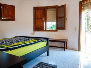 A bedroom with a bed, a bench, and a window with wooden shutters. - Villa 'Anina' close to the Sea with Pool & Wi-Fi (Denia)