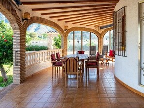 A covered patio with a table and chairs, arched brick walls, and a view of greenery. - Villa 'Anina' close to the Sea with Pool & Wi-Fi (Denia)