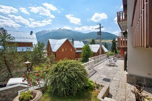 A residential area with houses, a balcony with outdoor furniture, and a mountain in the background.