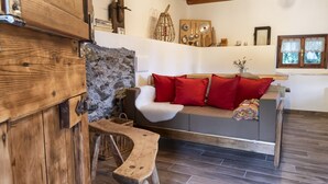 Un salon chaleureux avec un mur en pierre, un banc en bois et un canapé agrémenté de coussins rouges.