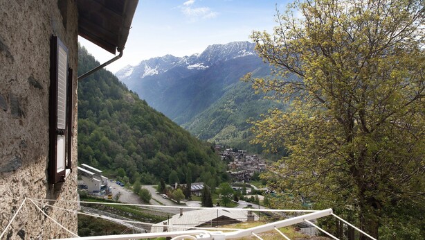 A mountain village with a view of snow-capped peaks, a winding road, and traditional buildings. - Apartment 'Bellavista' with Mountain View & Garden (Chiesa In Valmalenco)