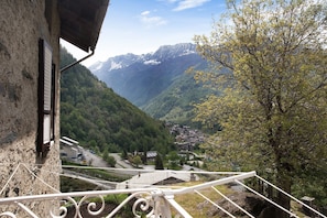 A mountain village with a view of snow-capped peaks, a winding road, and traditional buildings.