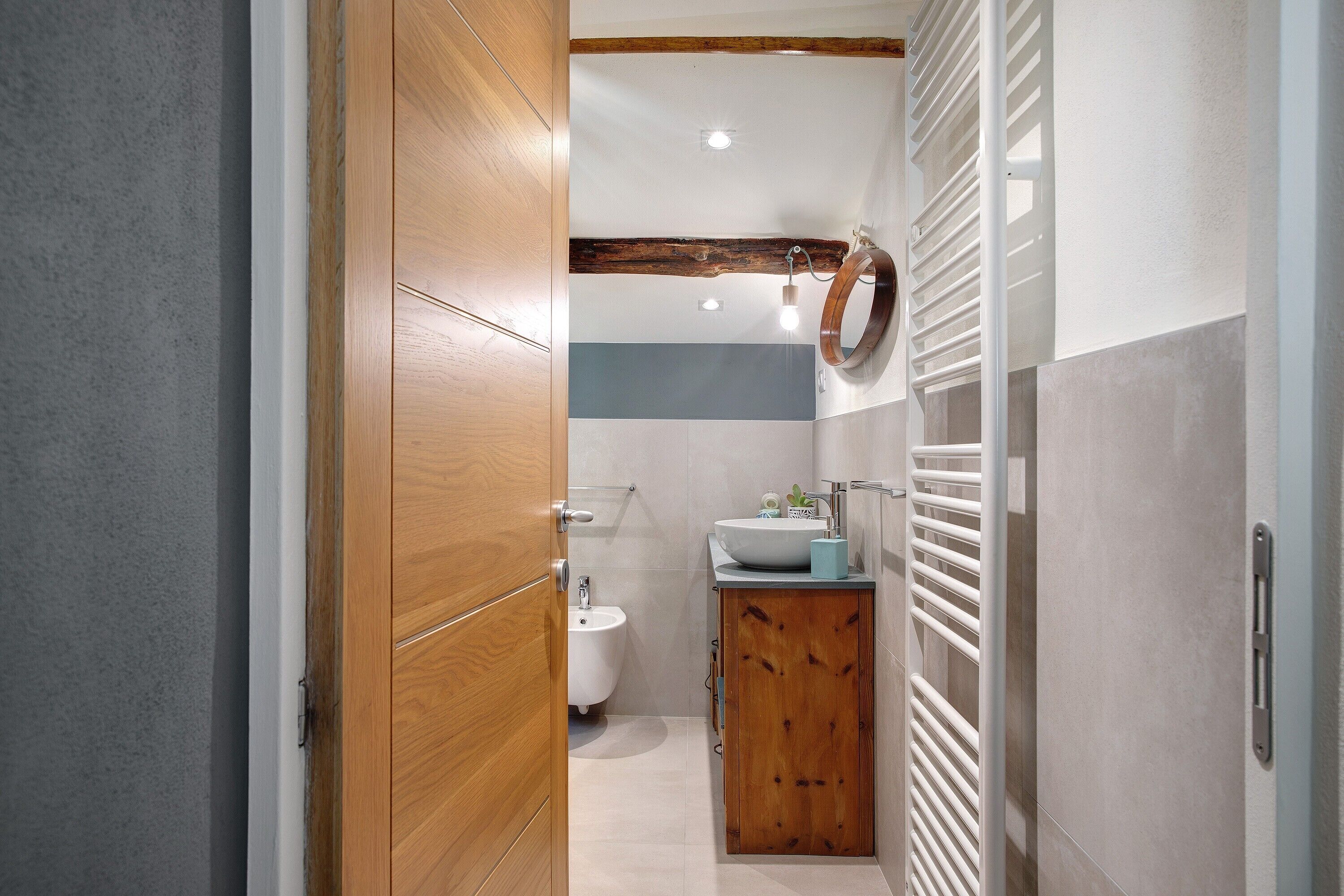 Een badkamer met een houten wastafel, een wasbak en een douchetoilet.
