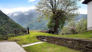 A stone pathway leading to a building with a view of mountains. - Apartment 'Bellavista' with Mountain View & Garden (Chiesa In Valmalenco)