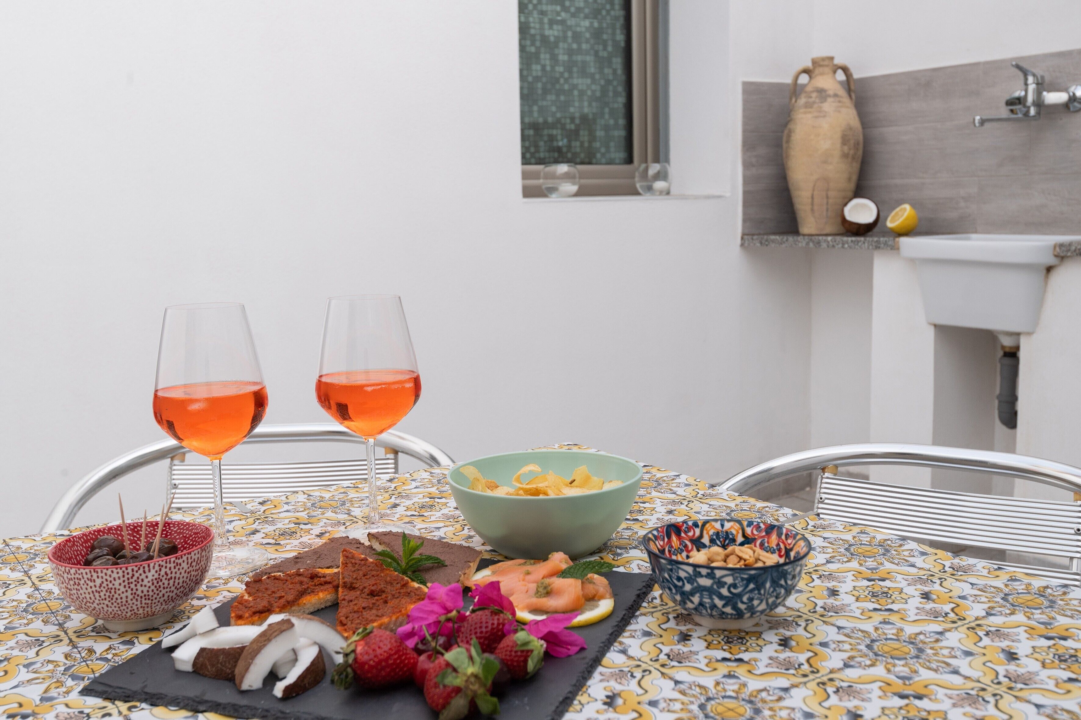 Un tavolo da pranzo con due bicchieri di bevanda rossa, ciotole di snack e una fetta di torta.