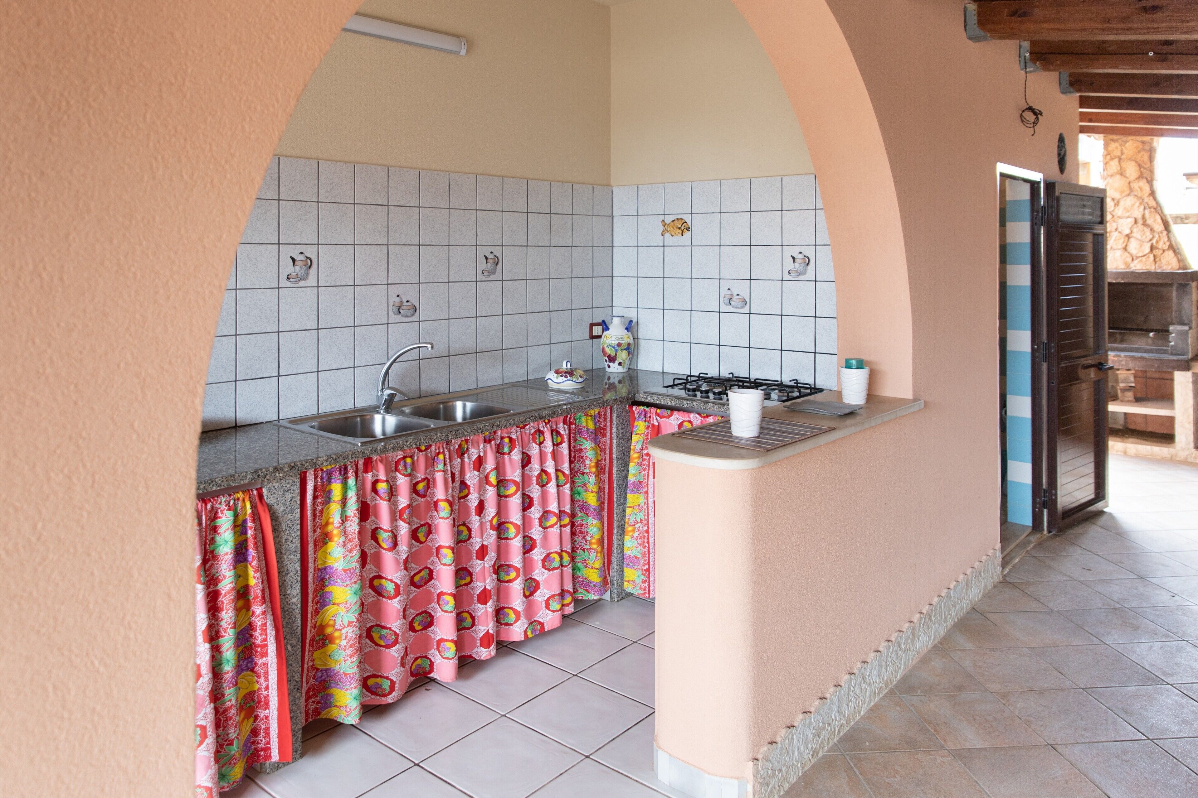 Cuina amb frontissa de rajola, forns a gas, un rentaplat i un forn de pizza.