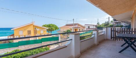 A balcony with a view of the sea, a wooden table, and a railing.