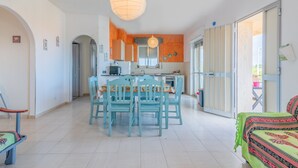 Un grand espace de vie comprenant un coin repas avec une table, des chaises et un canapé. Il y a également une cuisine équipée de placards et dotée d’une fenêtre.