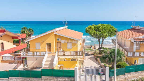 Un bâtiment situé sur la côte, doté d’un balcon, d’un escalier et offrant une vue sur la mer.