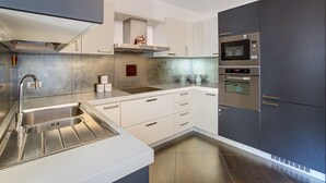 Una cucina moderna con lavello in acciaio inossidabile, forni doppi e forno a microonde.