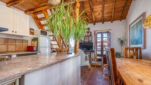 Una cocina con techo de madera, una isla central, armarios blancos y una silla roja.