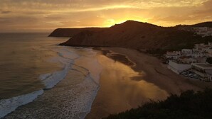 Un paisaje costero con una playa, un acantilado y edificios.