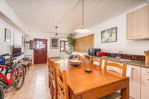 A dining area with a wooden table, chairs, a TV, and a red door.