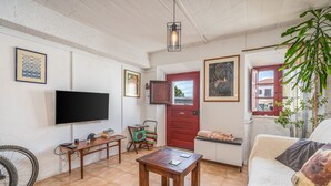 A living room with a TV, wooden table, sofa, and a red door. - Holiday Home "Casa da Praia 2" with Sea View, Terrace & Wi-Fi (Budens)