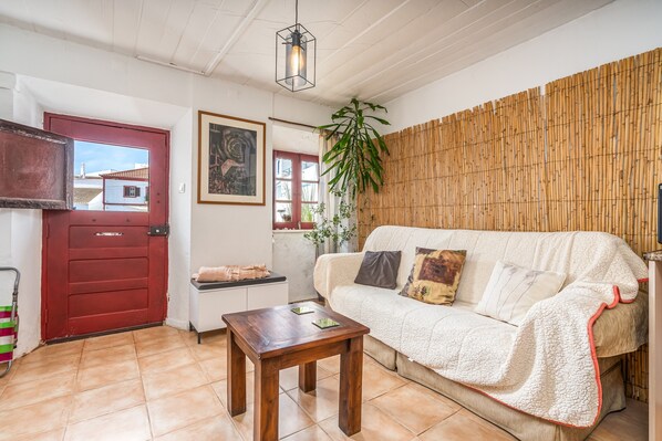 Un salon chaleureux avec une porte rouge, un canapé blanc, une table en bois et une grande plante.