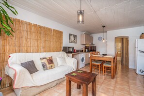 A cozy living area with a sofa, wooden dining table, and a washing machine.