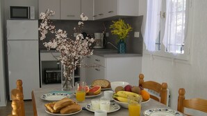 Una mesa de desayuno con platos de comida, un florero con flores y un microondas en la encimera.