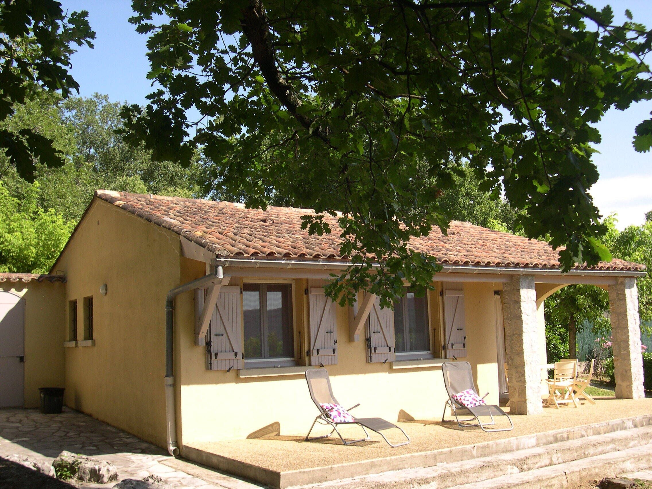 A two-story building with a tiled roof and a balcony with two chairs.