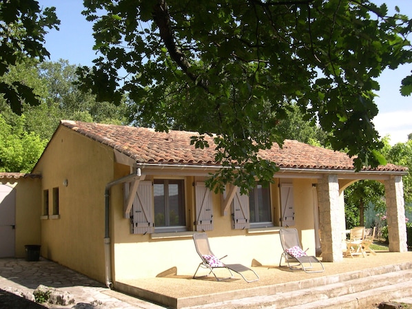 A two-story building with a tiled roof and a balcony with two chairs.