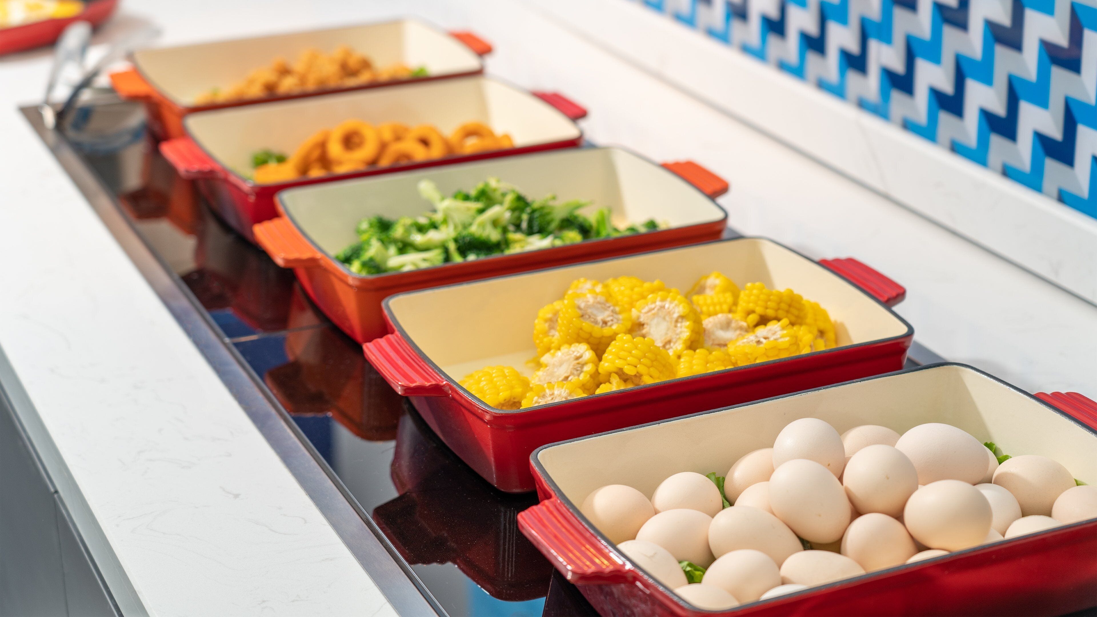 A buffet table with various food items in red containers.