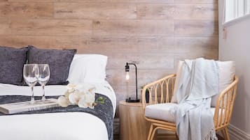 A bedroom with a bed, two bedside tables, a chair, a lamp, and a window.