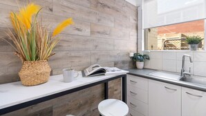 A modern kitchen with a wooden backsplash, a white countertop, a sink, and a window with a view of the outside. - Hidden Cozy Gem In Caulfield North (Caulfield North)