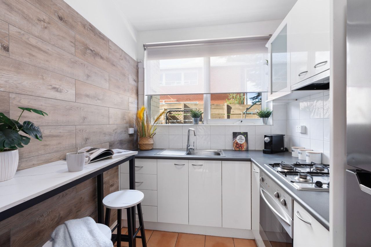 A compact kitchen with a wooden backsplash, a window, and a stove.