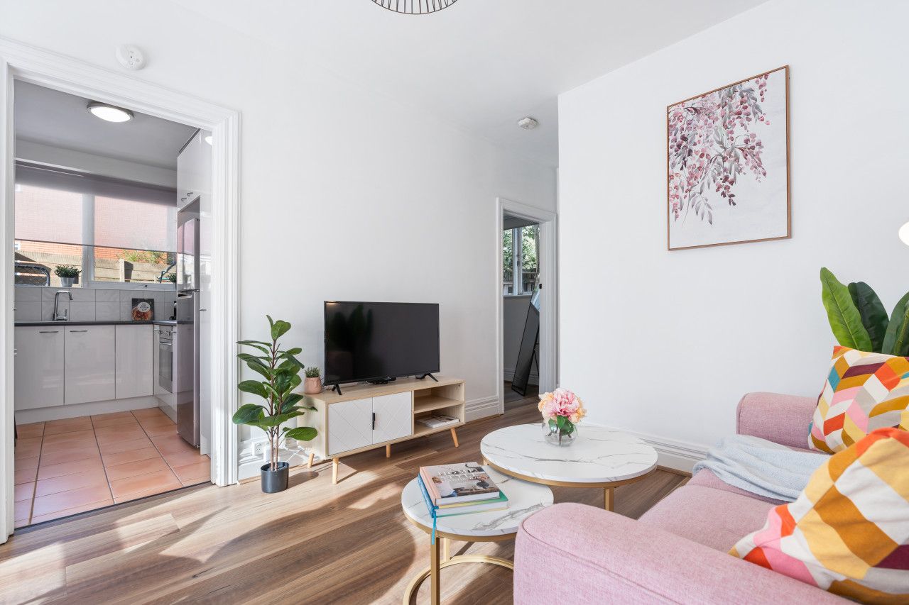 A modern living room with a flat-screen TV, a sofa, a coffee table, and a potted plant.