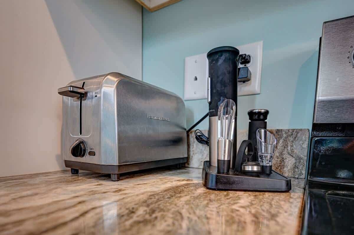 Una cocina con tostadora, cafetera y licuadora sobre una encimera de mármol.