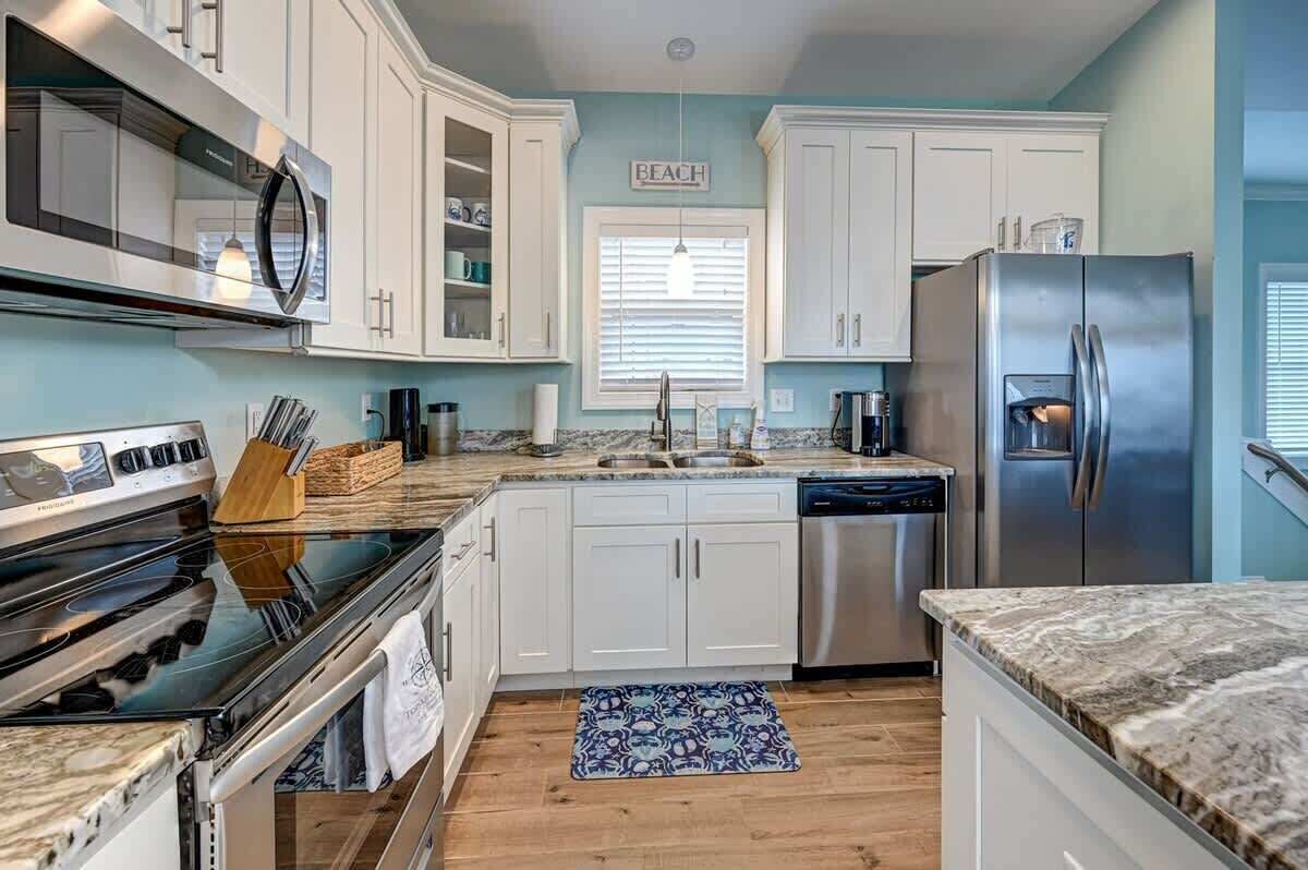 Una cocina moderna con armarios blancos, electrodomésticos de acero inoxidable y una pared de acento azul.