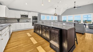 A spacious kitchen with white cabinets, a large island, and a view of the ocean.