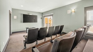 Una sala conferenze con schermo piatto, file di sedie, pavimento in moquette e una porta che dà su un'area esterna.