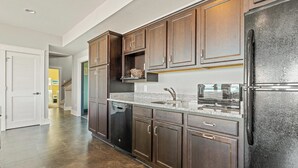 A kitchen with dark wooden cabinets, a stainless steel refrigerator, and a granite countertop.