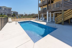 A rectangular swimming pool with a wooden deck and lounge chairs. - Surfside Retreat Oceanfront  Home + Pets Stay Free! (Buxton)