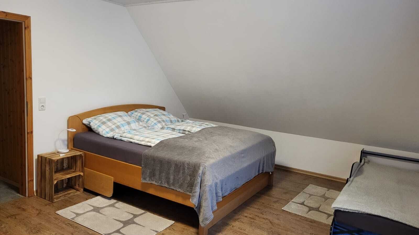 A small, cozy bedroom with a wooden bed, a nightstand, and a small table.