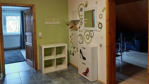 Une pièce avec un plafond en bois, un mur vert et un meuble blanc décoré de motifs représentant des chaussures.