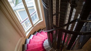 Eine Wendeltreppe mit rotem Teppich, Metallgeländer und Blick auf den Außenbalkon.