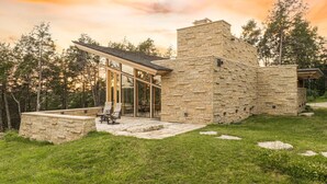 A stone building with a glass extension, outdoor seating, and a stone pathway.