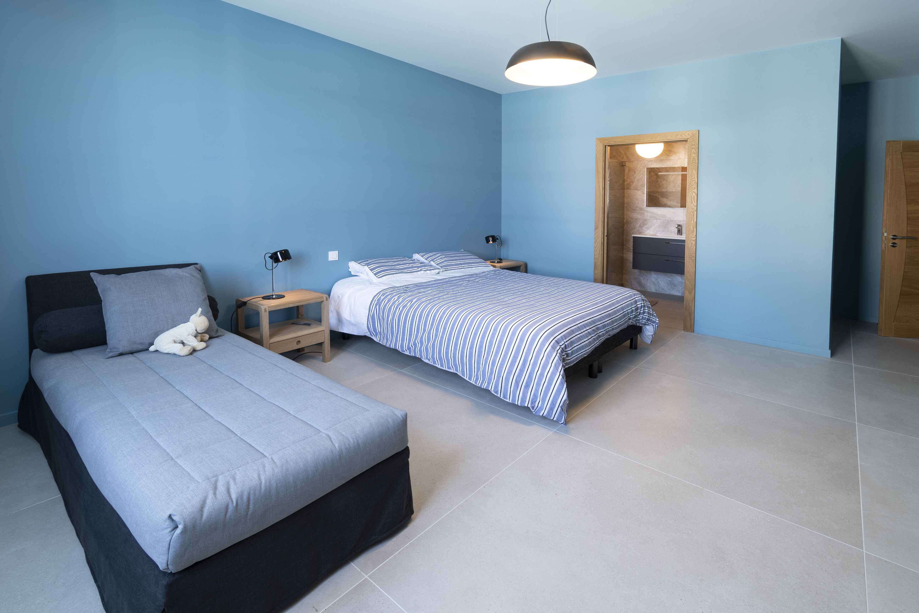 Ein Schlafzimmer mit zwei Betten, einem Nachttisch mit Lampe und einem Holzschrank.