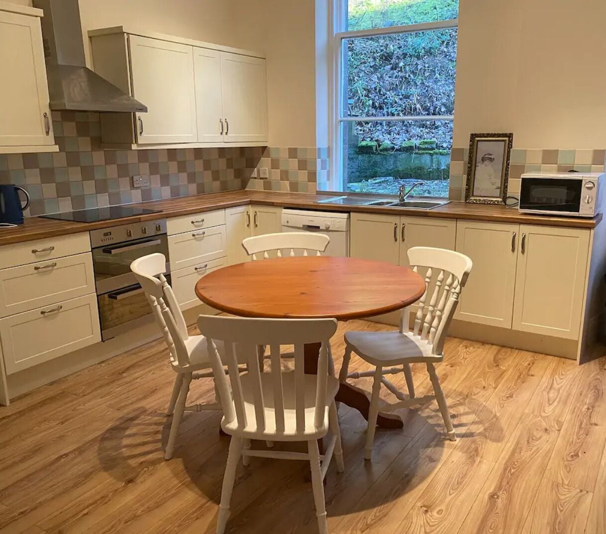 A kitchen with white cabinets, a wooden dining table, and chairs.