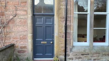 A stone building with a dark blue door, a window, and a small potted plant.