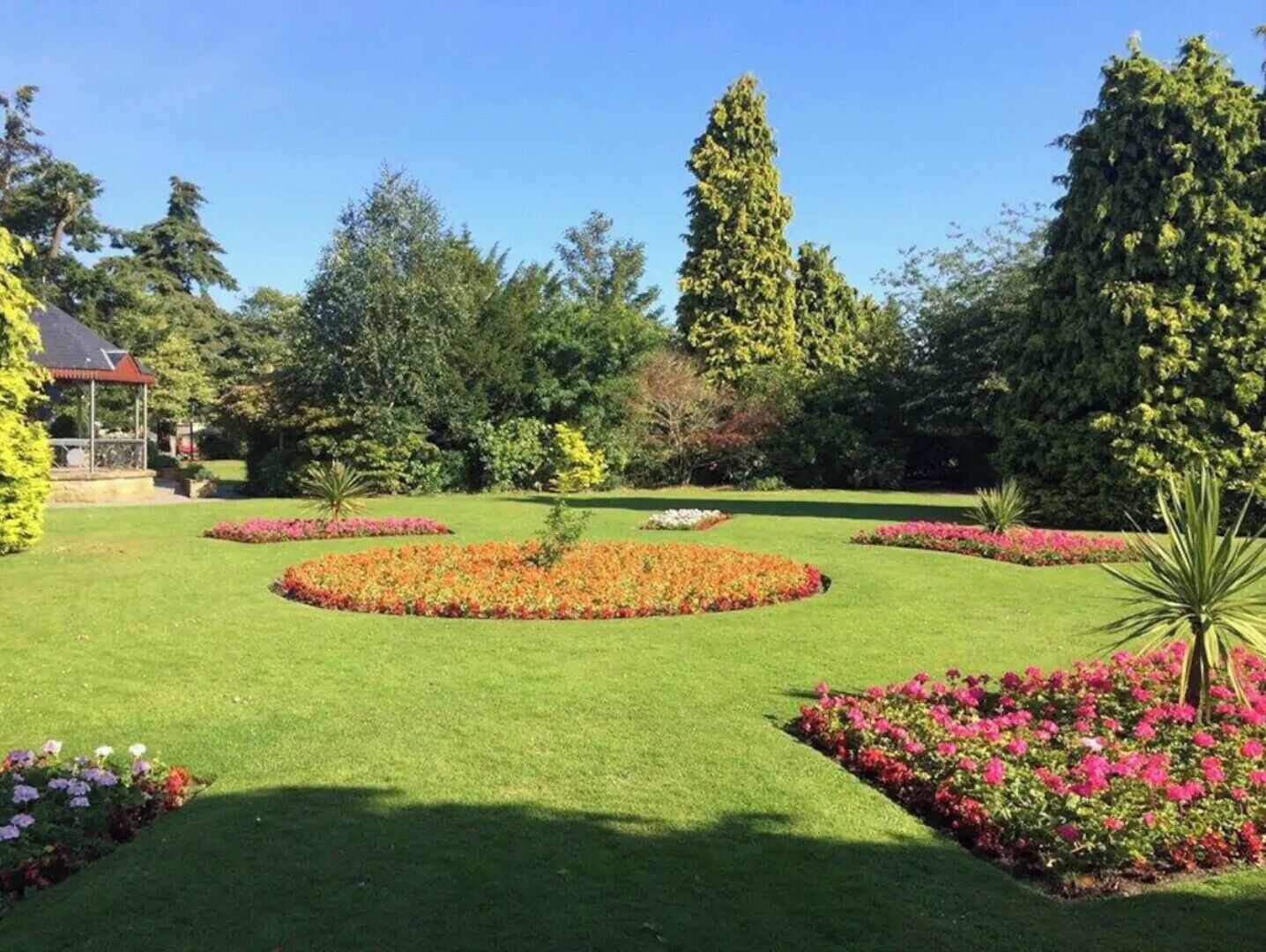 A well-maintained garden with a gazebo, manicured lawns, and various flowering plants.