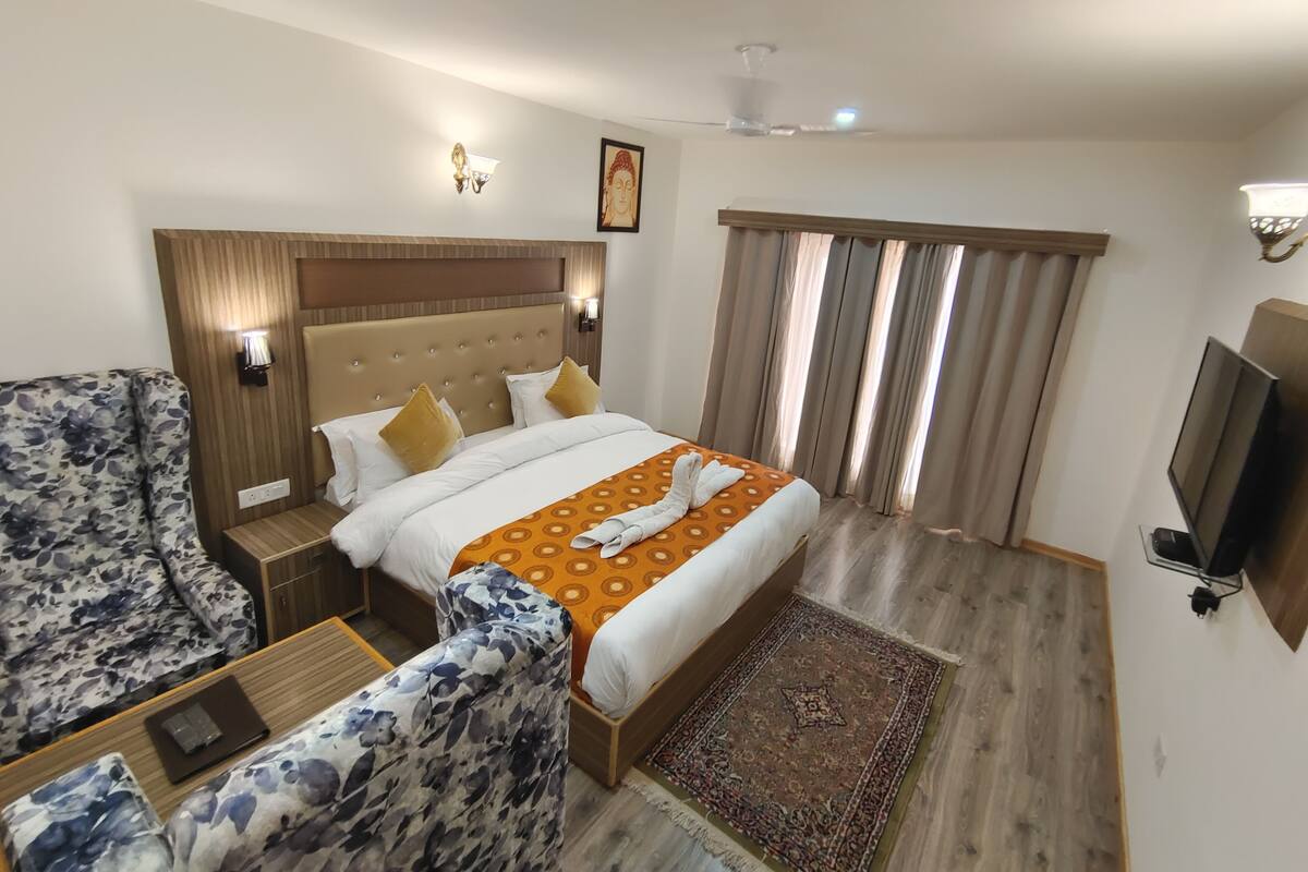 A hotel room with a bed, a sofa, a TV, and a ceiling fan.