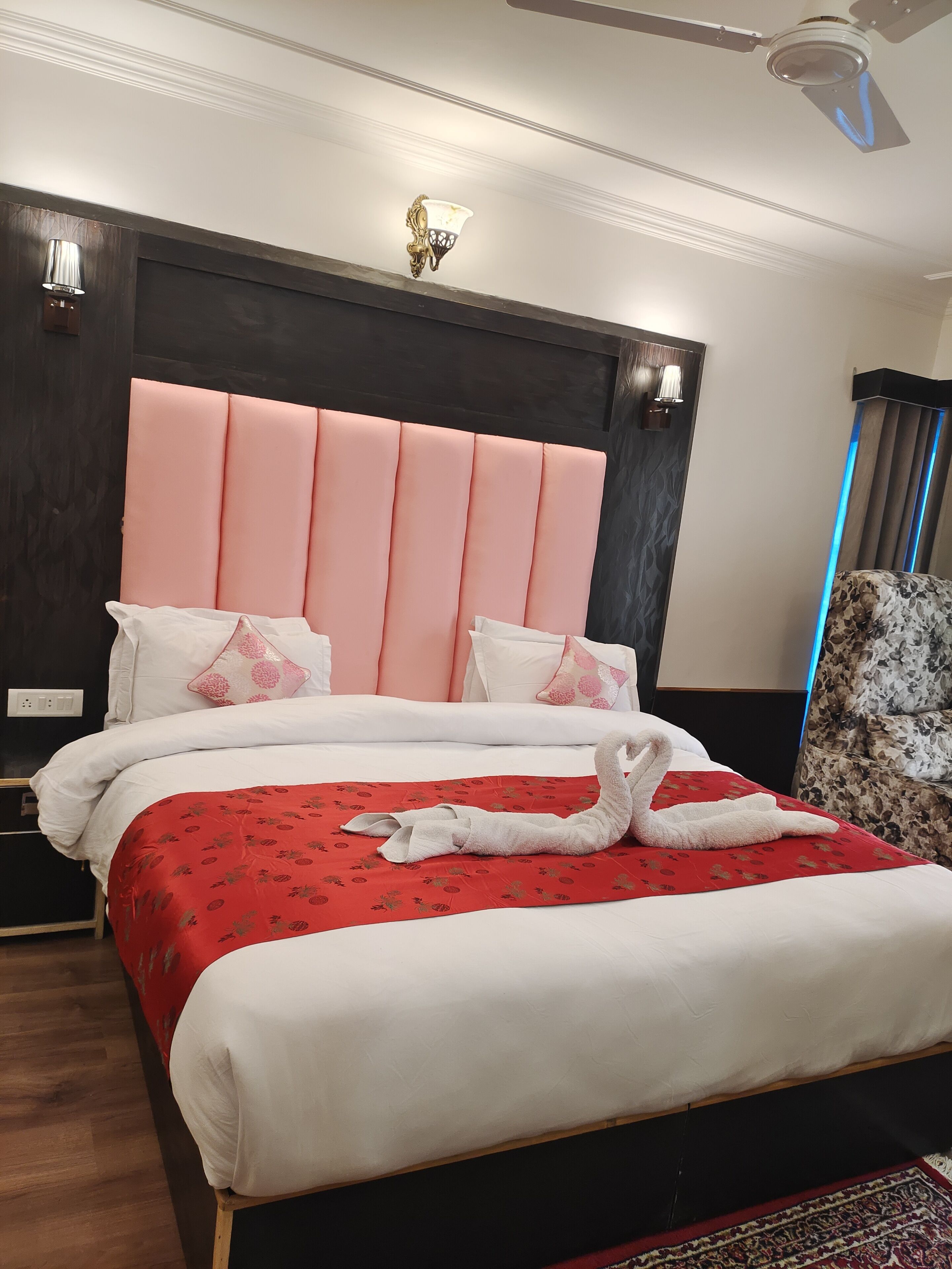 A hotel room with a large bed, a headboard, and a wall-mounted light fixture.